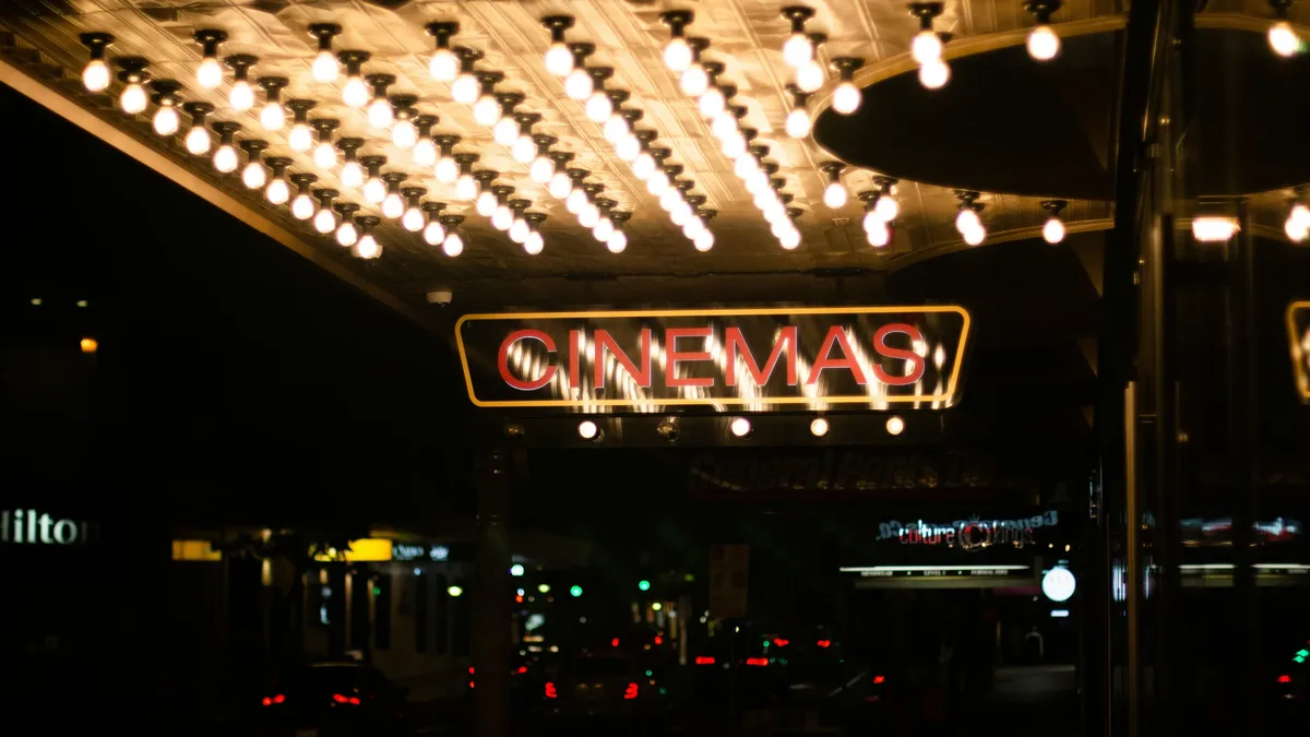 A movie theater entrance with a sign reading "CINEMAS" and a row of lights above it.